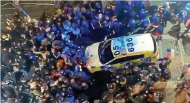  ??  ?? Mindless: Revellers surround a police car after bars shut down for a month