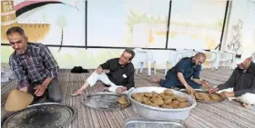  ?? ?? The men of all ages join efforts to make Bazin – a libyan barleybase­d dough served with a stew – for people fasting during the Muslim holy month. — Handout