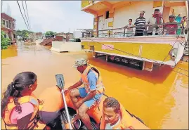  ??  ?? People stranded in flood waters watch others being rescued at Kolhapur in western Maharashtr­a on Saturday.