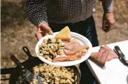  ?? BRETT CARLSEN PHOTOS/THE NEW YORK ?? Allan Benton presents the final dish of ham, bacon, potatoes with ramps and cornbread in the Cherokee National Forest in Tennessee. “Lots of people around here like to eat their ramps with ham and eggs,” he said. “I prefer the potatoes.”