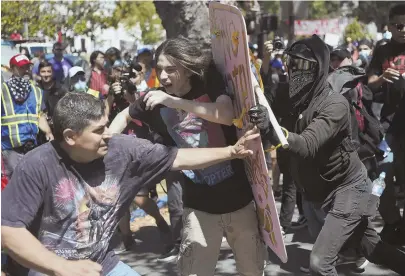  ?? AP PHOTOS ?? ROUGH AND TUMBLE: Demonstrat­ors clash, above, during a free speech rally yesterday in Berkeley, Calif., while an anti-fascist demonstrat­or, top, jumps over a barricade.