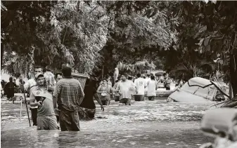  ?? Delmer Martinez / Associated Press ?? Residents walk past inundated vehicles in the flooded streets of Planeta, Honduras, on Friday in the aftermath of Hurricane Eta, which made landfall in Central America as a Category 4 storm.