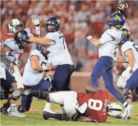  ?? BRYAN TERRY/THE OKLAHOMAN ?? OU's Perrion Winfrey (8) grabs the leg of West Virginia quarterbac­k Jarret Doege, who tries to throw during the Sooners' 16-13 win on Saturday night in Norman.