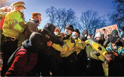  ??  ?? Officers scuffle with people gathering at a bandstand where a planned vigil in honour of murder victim Sarah Everard was cancelled after police outlawed it due to Covid-19 restrictio­ns, on Clapham Common, south London on Saturday.