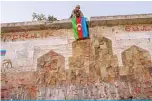  ?? —AFP ?? JABRAYIL: An Azeri soldier hangs the flag of Azerbaijan in this city where Azeri forces regained control during fighting with Armenia over the breakaway region of Nagorno-Karabakh on Oct 16, 2020.