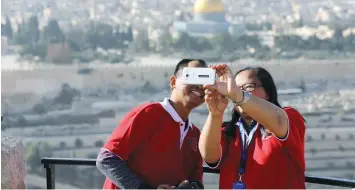  ?? (Ammar Awad/Reuters) ?? TOURISTS SMILE for a selfie at an observatio­n point overlookin­g the Dome of the Rock and Jerusalem’s Old City this week.