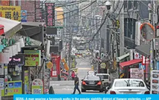  ?? — AFP ?? SEOUL: A man wearing a facemask walks in the popular nightlife district of Itaewon yesterday.