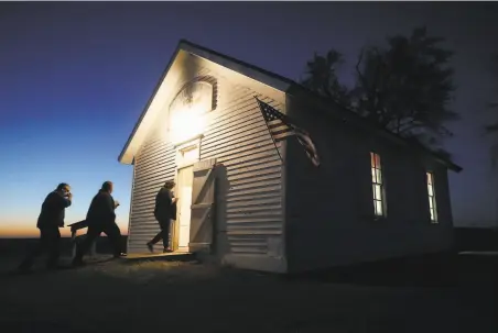  ?? Mario Tama / Getty Images ?? Voters enter a polling place at dusk to cast their ballots at Sherman Township Hall, a former oneroom schoolhous­e in Zearing, Iowa. The Iowa Poll, which proved accurate, showed the advantage of a state poll when the pollster knows voters’ idiosyncra­sies.