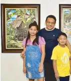  ??  ?? Painter Teody Boylie Perez with his kids Ivana Megumi and Yohane Samuel beside his paintings “Nipa Hut” (left) and “Talicud” (right). His art, he says, is an expression of his appreciati­on for God’s creation.
