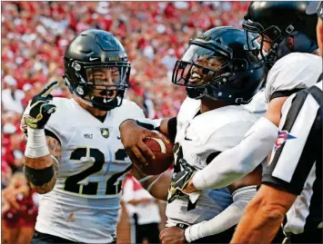  ?? [PHOTOS BY SUE OGROCKI/THE ASSOCIATED PRESS] ?? Army quarterbac­k Kelvin Hopkins Jr., center, celebrates with teammates Calen Holt (22) and Camden Harrison, right, after scoring against Oklahoma on Saturday in Norman, Okla. Combining an old-school offensive system with advanced analytical game management, Army has become a model of efficiency in college football.