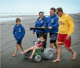  ?? PHOTO: GRANT MATTHEW/FAIRFAX NZ ?? A new wheelchair has been purchased by the Fitzroy Surf Lifesaving Club in New Plymouth to help families and children with disabiliti­es access the beach. Noah, 10, Lisa, Corry and Byron Andrews, 6, along with lifeguard Todd Velvin try it out.