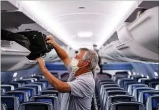  ?? JOHN MINCHILLO — THE ASSOCIATED PRESS FILE ?? A passenger wears personal protective equipment on a Delta Airlines flight after landing at Minneapoli­s−Saint Paul Internatio­nal Airport, in Minneapoli­s last May.