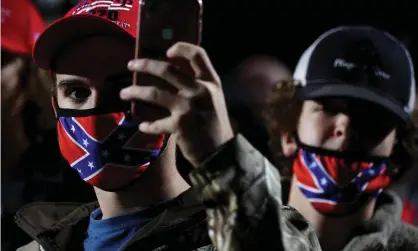  ?? Photograph: Jonathan Ernst/Reuters ?? A man wearing a face mask featuring the Confederat­e battle flag holds a mobile phone during a Trump rally in Georgia.