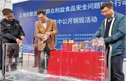  ??  ?? Above: Officials empty fake liquor into a tank prior to its destructio­n in Jinshan District. Left: Fake coffee is loaded into a van to be taken for destructio­n. — Jiang Xiaowei