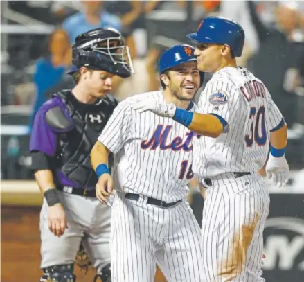  ?? Mike Stobe, Getty Images ?? Michael Conforto, right, celebrates with Travis d’Arnaud after Conforto’s three-run homer for the Mets in the seventh inning of Friday night’s series opener at Citi Field in New York against catcher Ryan Hanigan and the Rockies.