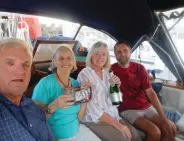  ??  ?? Kelaerin at anchor in New Zealand (top). With another cruising couple, Jim, left, and Joy, third from left, enjoy M&amp;M’S and Champagne, their traditiona­l post-passage treat.