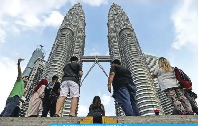  ??  ?? Tourists take pictures of the Petronas Twin Towers in Kuala Lumpur on November 13, 2017. — AFP
