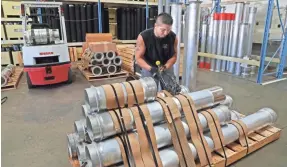  ?? MICHAEL SEARS / MILWAUKEE JOURNAL SENTINEL ?? Marcos Villalobos bands aluminum extension tubes for sewer cleaning onto a pallet for shipping to a customer at American Sewer Parts and Cleaning.