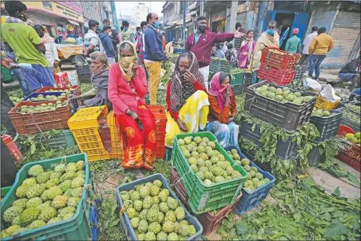  ?? (AP/Aijaz Rahi) ?? Fruit vendors cover their faces as a precaution against the coronaviru­s and wait for buyers at a wholesale market in Bengaluru, India. In the April-June quarter, government figures show, activity in trade, hotels, transport, constructi­on and communicat­ion declined by nearly half from a year earlier.