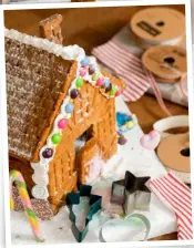  ??  ?? SWEET TREAT Turn your confection­ery into a delightful Christmas display with a home-baked house decorated with colourful sweets and a dusting of icing sugar.