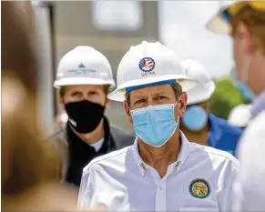  ?? ALYSSA POINTER / ALYSSA.POINTER@AJC.COM ?? Wearing a face mask and a hard hat, Gov. Brian Kemp tours temporary medical pods Friday at Northeast Georgia Health System in Gainesvill­e. He also visited a poultry processing plant. The industry has been a hotspot for COVID infections.