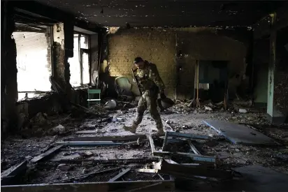  ?? BERNAT ARMANGUE — THE ASSOCIATED PRESS ?? A Ukrainian serviceman inspects a school damaged during a battle between Russian and Ukrainian forces in the village of Vilkhivka on the outskirts of Kharkiv in eastern Ukraine on Friday.