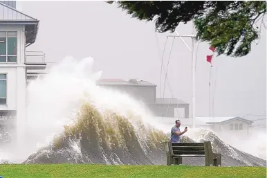  ?? GERALD HERBERT/ASSOCIATED PRESS ?? A man takes pictures of high waves along the shore of Lake Pontchartr­ain as Hurricane Ida nears New Orleans Sunday.