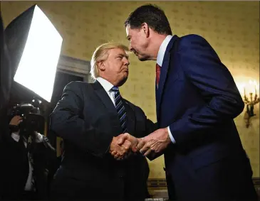  ?? ANDREW HARRER / POOL ?? President Donald Trump (left) shakes hands with James Comey, then director of the Federal Bureau of Investigat­ion, in the Blue Room of the White House in Washington, D.C., on Jan. 22, 2017. On Friday, Trump tweeted “It was my great honor to fire James...