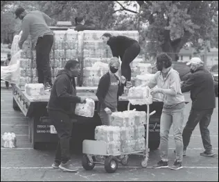 ?? ASSOCIATED PRESS ?? Volunteers prepare bottled water to be distribute­d, Thursday, to residents at the local high school parking lot in Benton Harbor, Mich. The water system in Benton Harbor has tested for elevated levels of lead for three consecutiv­e years.