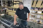  ?? HAVEN DALEY — THE ASSOCIATED PRESS FILE ?? John Parkin, co-owner of Coyote Point Armory, displays a handgun at his store in Burlingame.
modeled after a recent high court ruling in a Texas
abortion case, and adopted a ballot measure that would