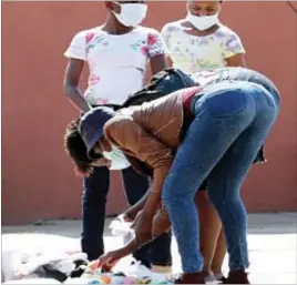  ??  ?? Women sample baby clothes for sale along Lobengula Street in Bulawayo yesterday. Some people prefer street shopping as they believe items available there are cheaper than those in shops (Picture by Nkosizile Ndlovu)