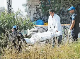  ??  ?? Personal forense recoge un cadáver hallado en Iztapalapa.