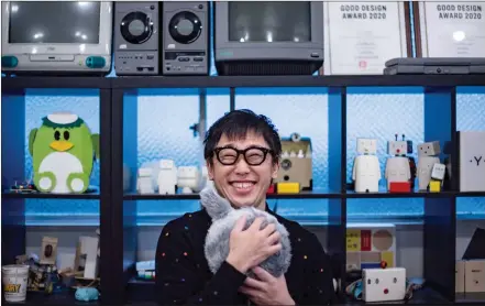  ??  ?? Aoki hugging robotic cushion Qoobo in a studio in Tokyo.