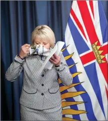  ?? The Canadian Press ?? Provincial Health Officer Dr. Bonnie Henry puts on her protective mask following details about the COVID-19 vaccine card set to arrive in mid-September were discussed at a press conference at provincial legislatur­e in Victoria.