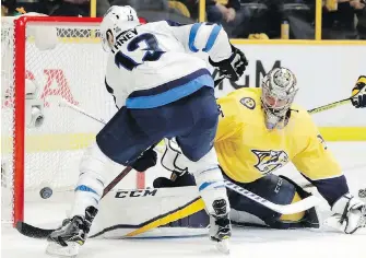  ??  ?? Jets winger Brandon Tanev slaps the puck past Predators goalie Pekka Rinne during the first period of Game 1 in Nashville, Tennessee, on Friday.