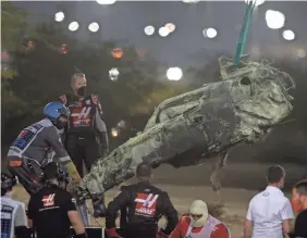  ?? TOLGA BOZOGLU/AP ?? A part of Haas driver Romain Grosjean’s car is taken after the crash at the start of the Formula One Bahrain Grand Prix on Sunday.