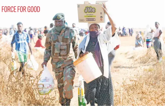  ?? Picture: Nigel Sibanda ?? A South African National Defence Force member helps carry a Waterworks resident’s donated food in Soweto yesterday.The social developmen­t department and Philani Community Centre donated 1 000 food parcels sponsored by the Food Bank.