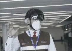  ??  ?? 0 An airport worker takes temperatur­es with a helmet scanner