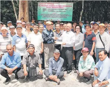  ??  ?? Nansian (standing front fourth right) presents a cheque to Teho while others look on.