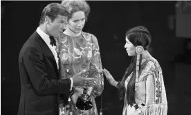  ?? Photograph: Bettmann/Bettmann Archive ?? Sacheen Littlefeat­her, right, refusing to take the award for best actor from Roger Moore and Liv Ullmann, 1973.