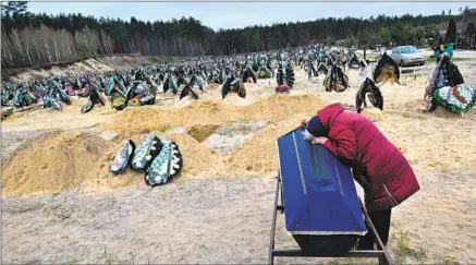  ?? Sergei Supinsky AFP/Getty Images ?? A WOMAN crouches over her husband’s coffin at a cemetery in Irpin, Ukraine, in April after the Russian invasion.