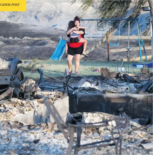  ?? DARRYL DYCK/THE CANADIAN PRESS/VIA THE ASSOCIATED PRESS ?? Kelsey Thorne holds her daughter Nevaeh Porter, 8, as they cry while viewing the remains of their home. The house, where they lived with Thorne’s parents, was destroyed by a wildfire on the Ashcroft First Nation, near Ashcroft, B.C., late Sunday.