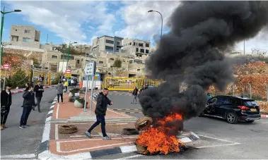  ?? (Eli Berlzon/Reuters) ?? SMOKE BILLOWS from a burning tire as residents demonstrat­e yesterday against a report that Israel may quarantine visitors from South Korea at a military base in Har Gilo.