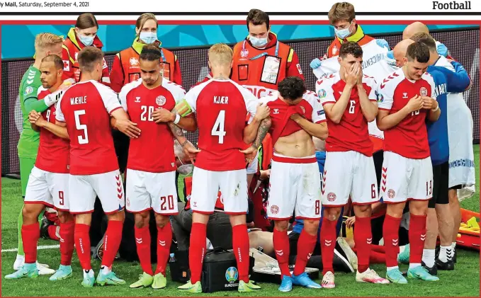  ?? REUTERS/GETTY IMAGES ?? Standing together: emotional Denmark players shield their stricken team-mate from view as he receives life-saving treatment on the pitch