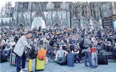  ?? FOTO: REUTERS ?? Viele Bahnreisen­de harrten mit ihrem Gepäck auf der Domplatte nahe des Hauptbahnh­ofs aus.