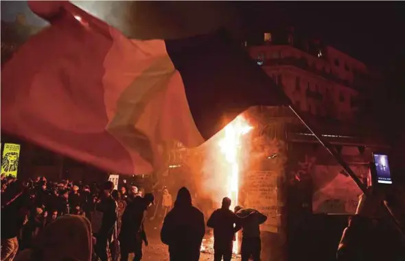  ?? AFP PIC ?? Demonstrat­ors standing next to a fire during a protest against the global security draft law in Paris on Saturday.