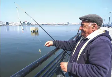  ?? — AFP photos ?? Men fish at an embankment of the Caspian Sea in Baku. Seals, once a common sight on Baku’s waterfront, have been declared endangered.