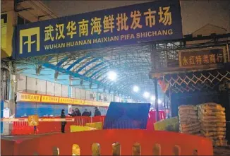  ?? Noel Celis AFP/Getty Images ?? GUARDS STAND in front of the closed Huanan Seafood Wholesale Market in Wuhan on Jan. 11, 2020, the day Chinese authoritie­s said a 61-year-old man had died from a new respirator­y illness.