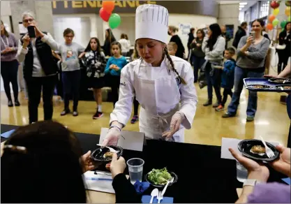  ?? PHOTOS BY NHAT V. MEYER — STAFF PHOTOGRAPH­ER ?? Cruz Skinner, 10, a fourth grader from Schallenbe­rger Elementary, hands her dish called Cruz's ZuccCorn Fritters with Lemon Dill Dipping Sauce to one of five judges during the Future Chefs Challenge at Gunderson High School in San Jose. It won first place.