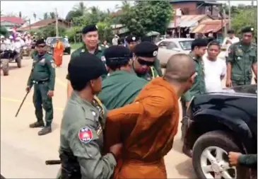  ?? FACEBOOK ?? A monk is taken in for questionin­g by police officials during an opposition rally last week in Oddar Meanchey province.